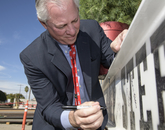 UA President Robert C. Robbins signs the final steel beam. (Kris Hanning/UAHS BioCommunications)